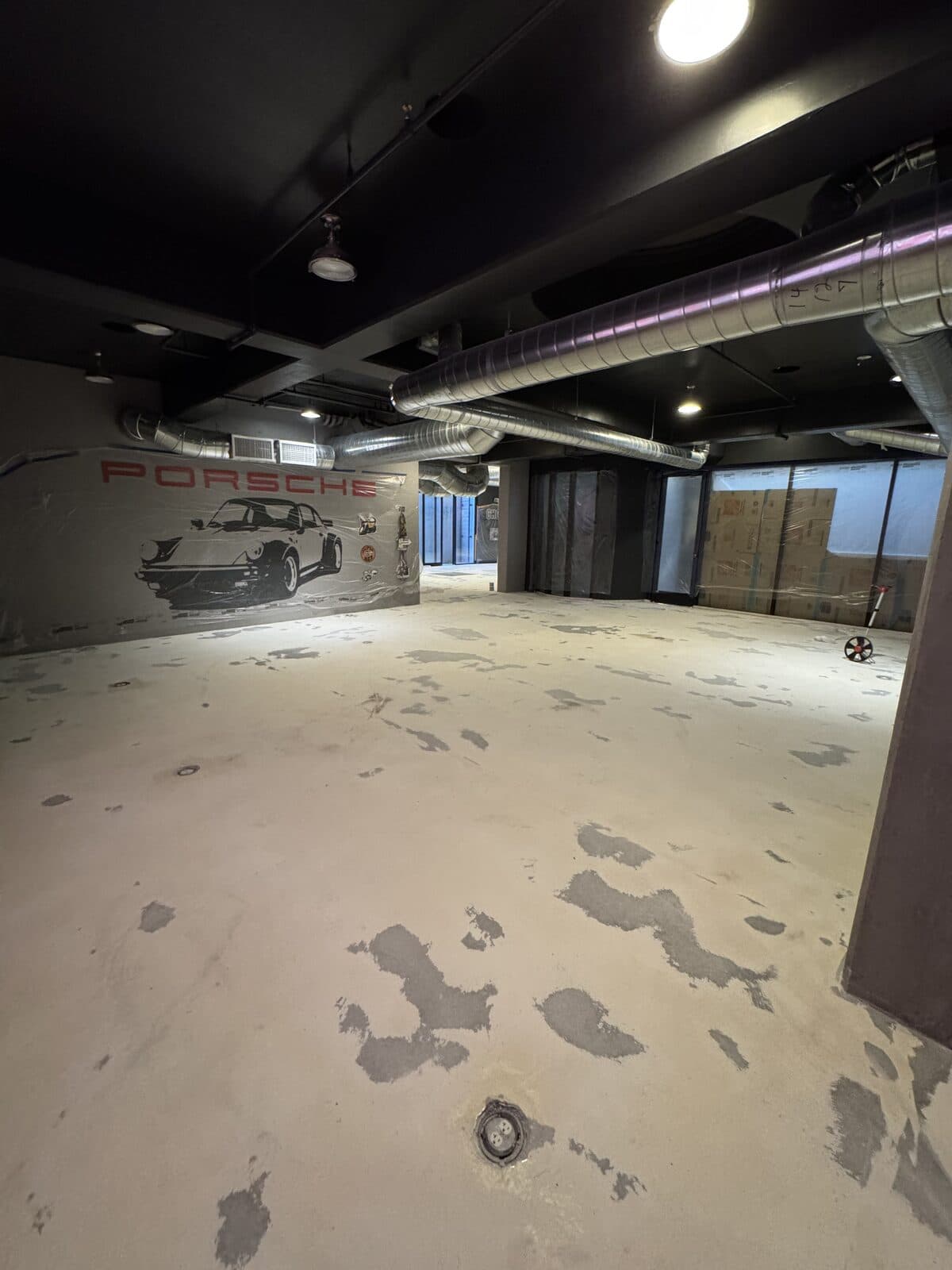 Commercial showroom concrete floor with Porsche mural before metallic epoxy coating by ProShield Epoxy in Las Vegas