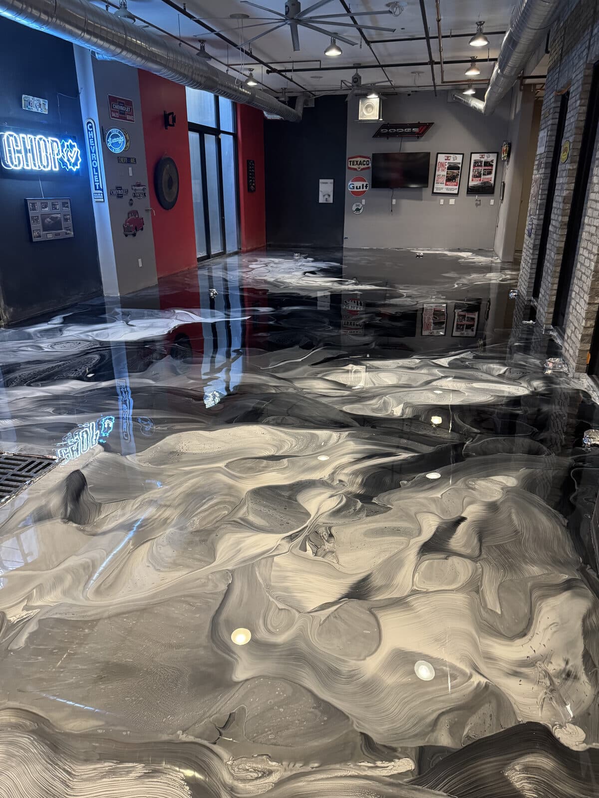 Metallic epoxy floor in Las Vegas commercial showroom showing swirl pattern and light reflections with neon signage — installed by ProShield Epoxy