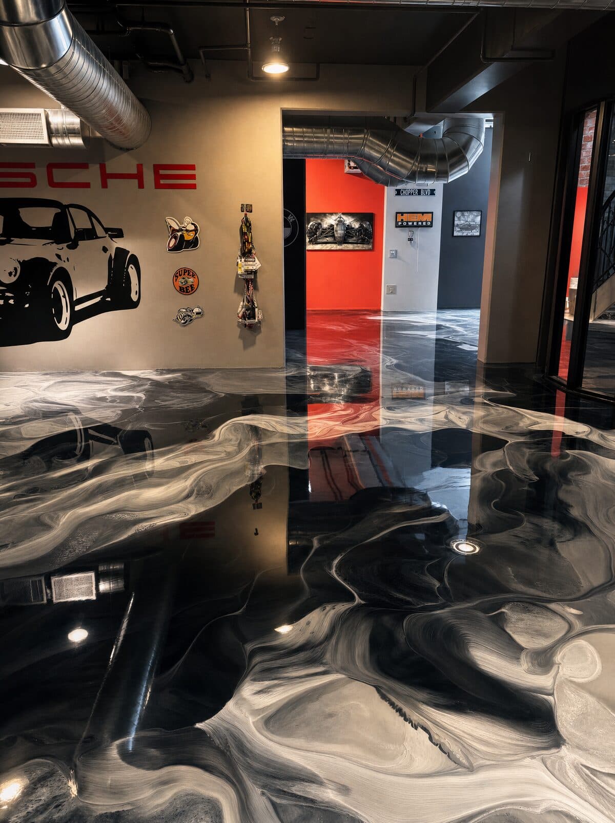 Metallic epoxy showroom floor installed by ProShield Epoxy in Las Vegas with deep silver and charcoal three-dimensional pattern reflecting neon lights and Porsche wall art