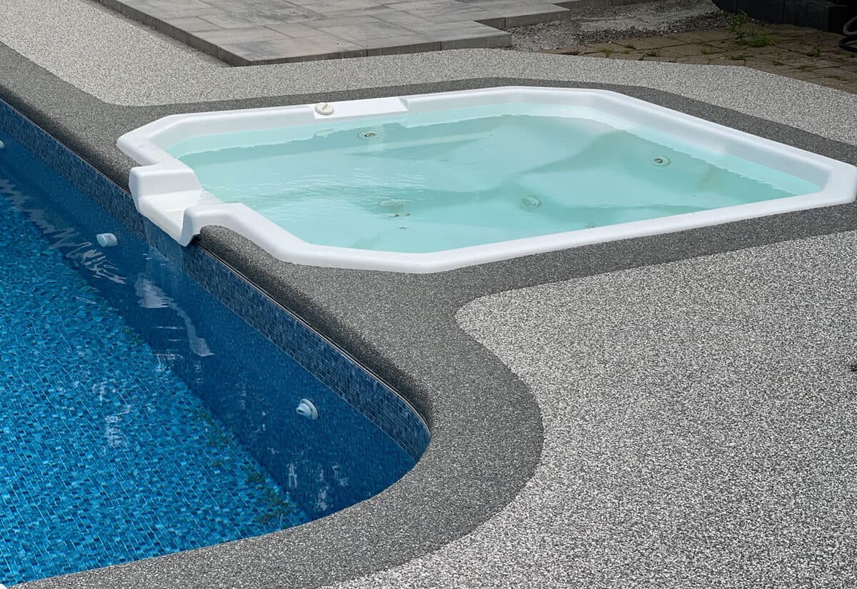 Gray two-tone rubber aggregate pool deck around a pool and hot tub — installed by ProShield Epoxy in Las Vegas