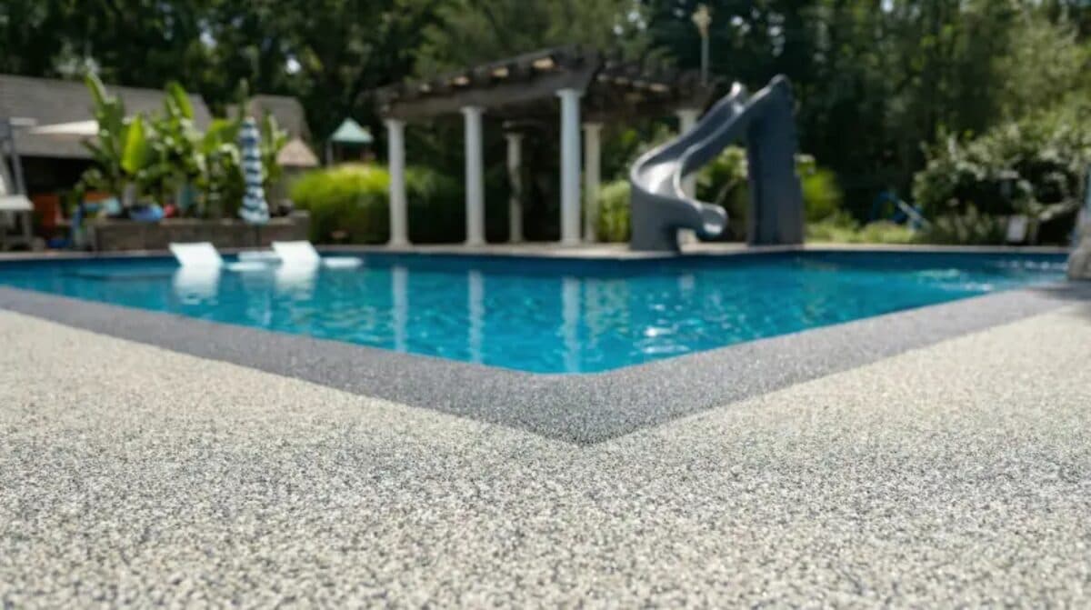 Completed gray rubber pool deck with slide and pergola in Las Vegas backyard — installed by ProShield Epoxy