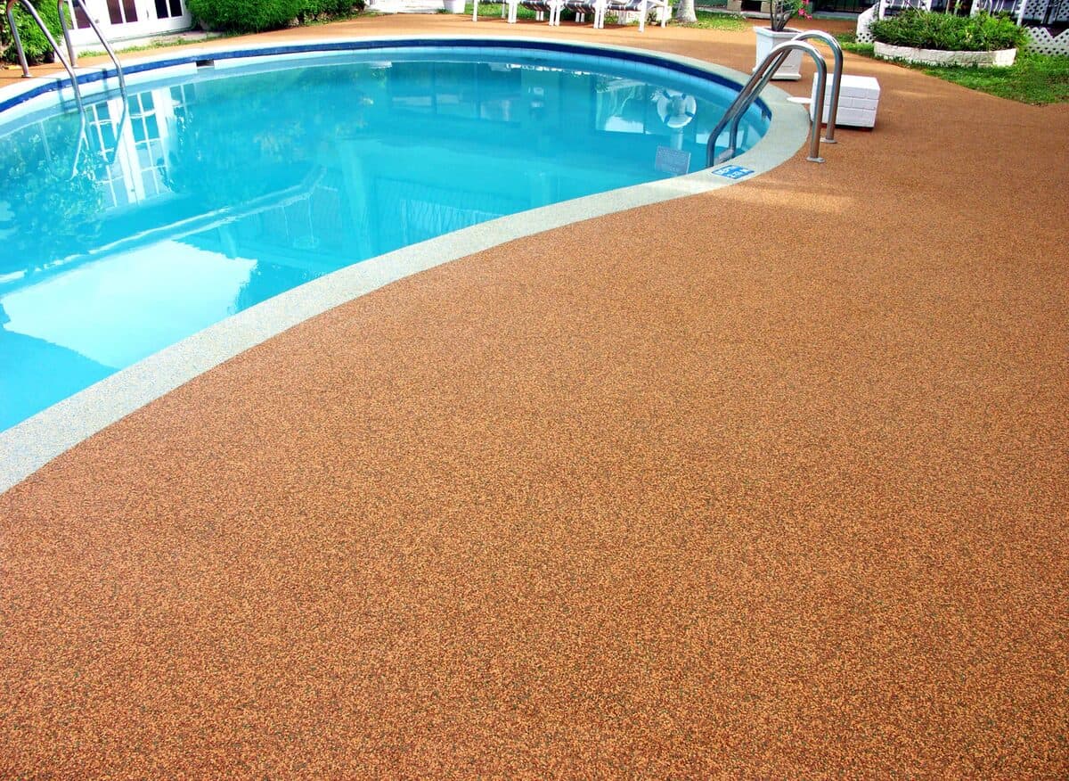 Terracotta-colored rubber aggregate pool deck showing warm copper tones around a Las Vegas pool — installed by ProShield Epoxy