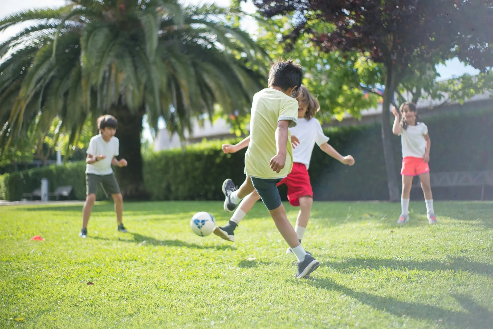 Children playing soccer on a lush green lawn
